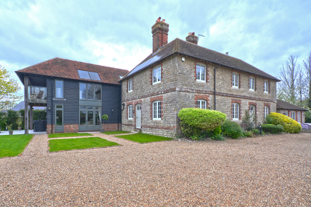 Exterior view of a beautiful detached property with new extension featuring dark cladding, large grey framed windows and balcony