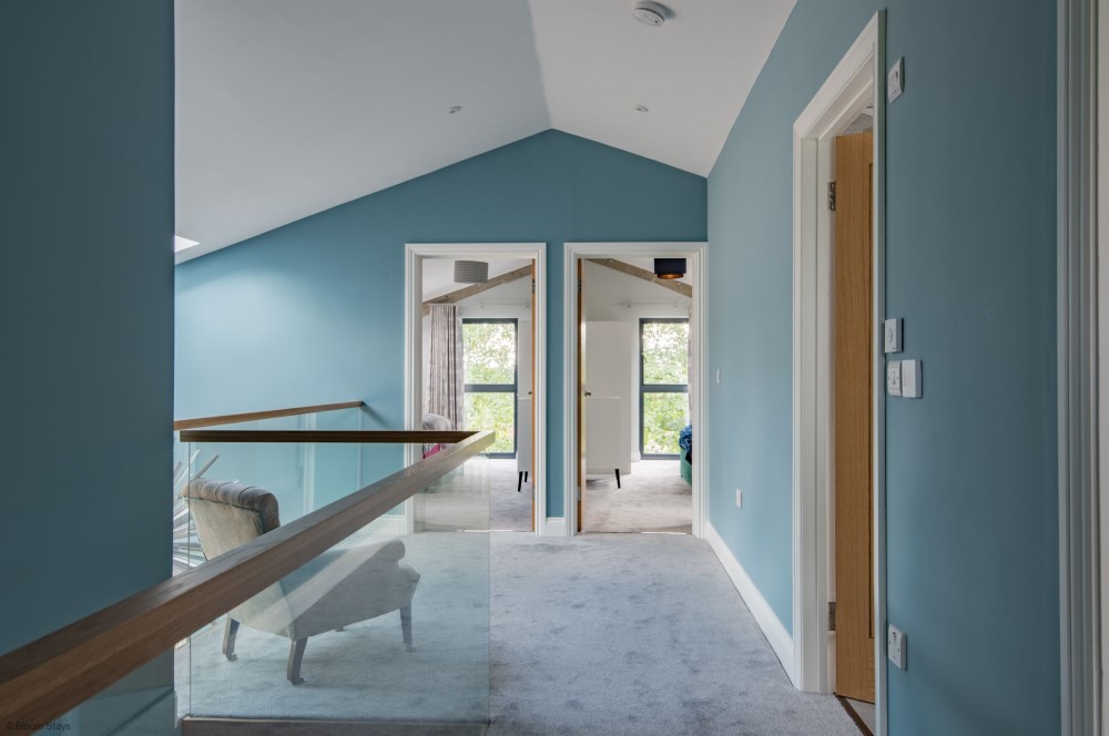 Stunning barn conversion holiday let interior view across landing with glass panel staircase - Vernacular Homes